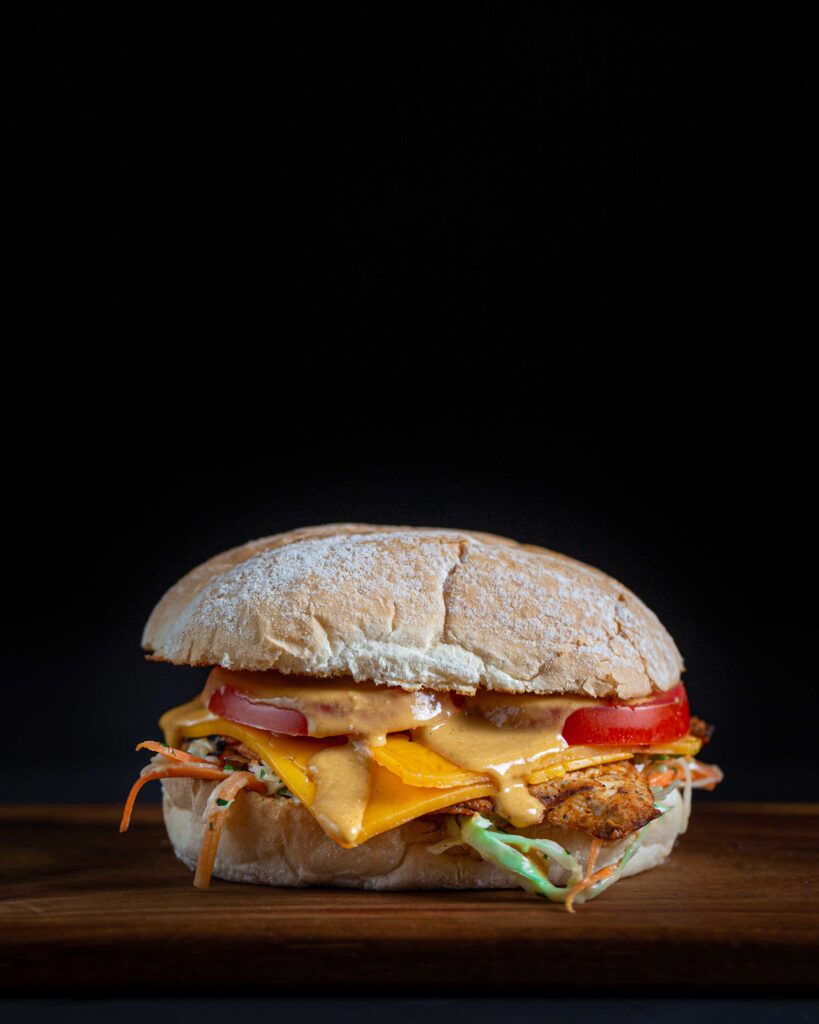 A mouth-watering burger with golden fries on a wooden board.
